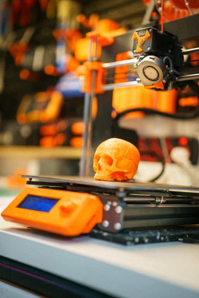 pexels-photo-17509939-17509939 A close-up of an orange 3D printed skull on a 3D printer, showcasing modern technology in a workshop setting.